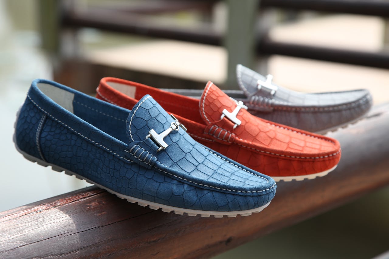 Fashionable leather loafers in various colors displayed on a wooden railing outdoors.